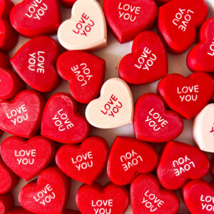 מבחר מגנטים בצורת לב בצבעים אדום ולבן עם הכיתוב "LOVE YOU", מעוצבים בהשראת סוכריות סודה.