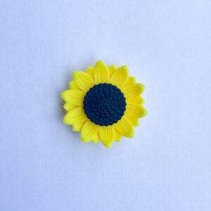 סיכת חמנייה צהובה-שחורה בעיצוב תלת מימד על רקע לבן